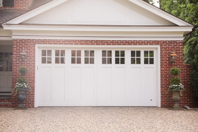 White carriage style garage door with upper windows on a brick home