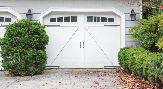 White carriage house garage door with upper windows and decorative hardware
