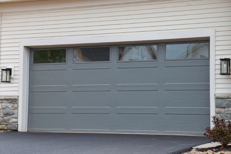 Traditional gray garage door with rectangular windows on a residential home